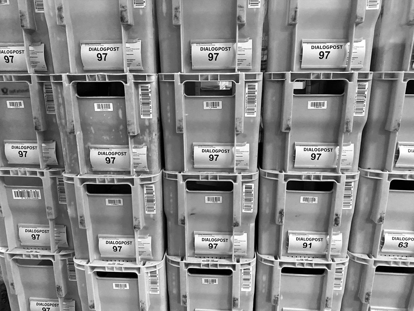 Gestapelte Postbehälter mit Dialogpost-Einlieferungsscheinen der Mühlbauer Media GmbH